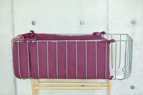 Bettumrandung aus Musselin in Purpur im Babybett.