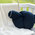 Eine Wickeltischrolle Musselin dunkelblau der KraftKids GmbH ruht auf einer weichen, cremefarbenen Decke, die über einer weißen Bank drapiert ist, mit einem verschwommenen grünen Hintergrund im Freien.