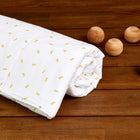 Ein weißes KraftKids Bettwäscheset Musselin "gelbe Zitronen" aus 100% Baumwolle mit kleinem gelben Zitronenmuster liegt aufgerollt auf einer Holzfläche neben fünf runden, hellen Holzkugeln.