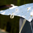 Nahaufnahme des KraftKids Sonnensegel Musselin gelbe Zitronen Kinderwagenverdecks mit gelbem Zitronenmuster, das optimalen Sonnenschutz für Babys bietet. Der Hintergrund zeigt verschwommenes Grün.