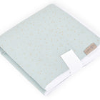 Eine gefaltete grüne Reisewickelunterlage aus Musselin mit goldenen Punkten und einem weißen Band, mit einem KraftKids-Etikett an der Ecke. Ideal als Reiseauflage Baby zum Wechseln für unterwegs.