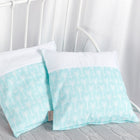 Zwei dekorative KraftKids Kissenbezüge weiße Pfeile auf Mint mit weißen und mintfarbenen Abschnitten, die mit einem weißen Pfeilmuster versehen sind, liegen auf einer hellgrauen Decke auf einem weißen Metallbettgestell mit weißen Vorhängen im Hintergrund.