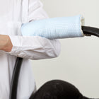 Eine Person im weißen Hemd trägt eine Babyschale mit dem KraftKids Armschoner "kleine Blätter hellblau auf Weiß" mit hellblauem und weißem Blattmuster und sicherem Klettverschluss für Komfort.