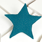 Ein Sternkissen Musselin mit goldenen Punkten auf Petrol von KraftKids liegt auf großen, weißen rechteckigen Blöcken - perfekt fürs Kinderzimmer.