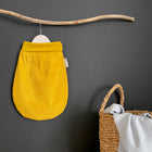 Ein KraftKids Strampelsack Herbst Winter Cord Breitcord Gelb Senf hängt an einem Holzstab an einer dunklen Wand, daneben stehen ein Korb und eine hellgraue Decke - ideal für gemütliche Herbst- und Winternächte.