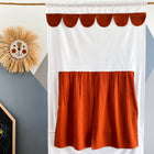 Das KraftKids Puppentheater Kasperletheater Doppelkrepp Rot Herbstrot mit Teleskopstange hängt neben einer Strohlöwen-Wanddeko und einer Tafel mit "ZOE" vor einer geometrisch gemusterten Wand.