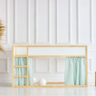 Ein minimalistisches Kinderetagenbett mit hellem Holzrahmen und KraftKids Hochbettvorhänge Set 2+1 Musselin goldene Punkte auf Grün für das Kura Bett steht in einem hellen Raum mit weiß getäfelten Wänden, Pampasgras in einer Korbvase und zwei Holzhockern.