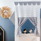 Ein Kinderzimmer mit dem KraftKids Puppentheater Kasperletheater Musselin grau Pusteblumen inkl.. Teleskopstange, zwei Puppen hinter grauen Vorhängen, einer lächelnden Strohsonne als Wanddekoration und einem Teil einer Kreidetafel mit bunten Zeichnungen auf der linken Seite.